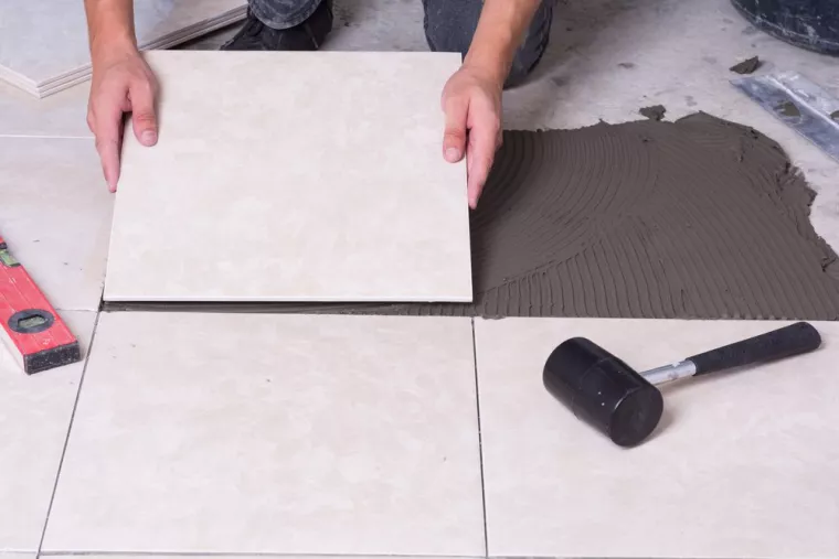 Professionnel pour pose de carrelage beige dans salle de bain dans le cadre d'une rénovation d'appartement, Pays de Gex, Lion Constructions